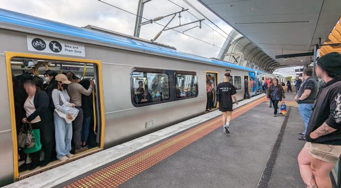 Crowded train waiting at a platform. Some passengers have chosen not to board.